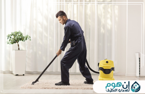 تنظيف الأرضيات والسيراميك بالدمام 0559016158 شركة إين هوم للتنظيف عامل ينظف أرضية المنزل بالمكنسة الكهربائية داخل غرفة مضيئة ومرتبة.