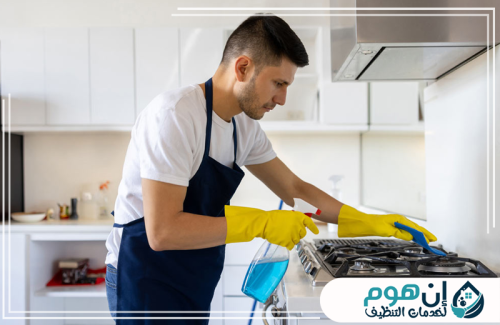 تنظيف أفران ومطابخ بالرياض 0559016158 شركة إين هوم للتنظيف عامل ينظف موقد المطبخ باستخدام منظف مخصص وقطعة قماش لإزالة الدهون.